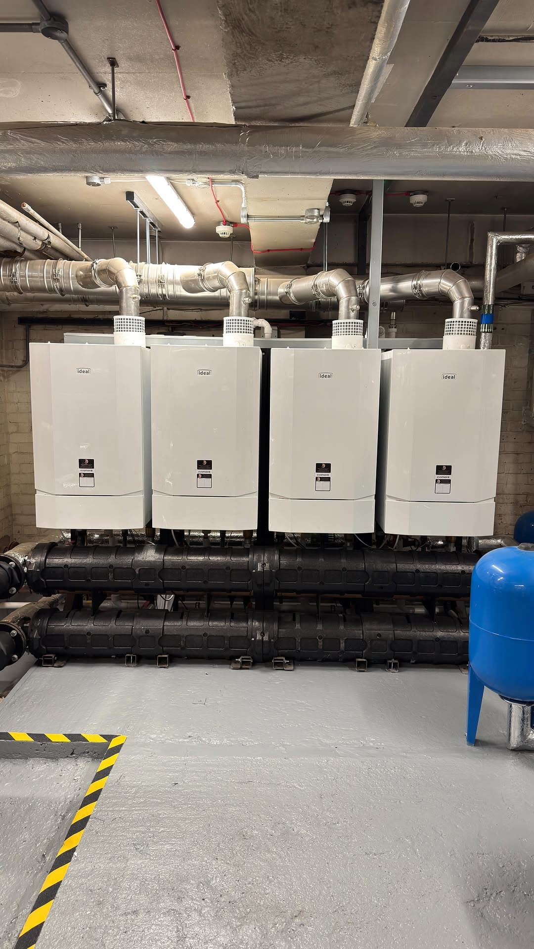 Care home plant room with three new boilers and a painted floor after a strip-out and rebuild