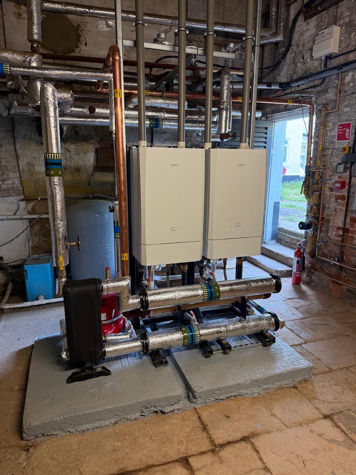 Two Keston Heat 2 boilers straight on, insulated headers on a plinth