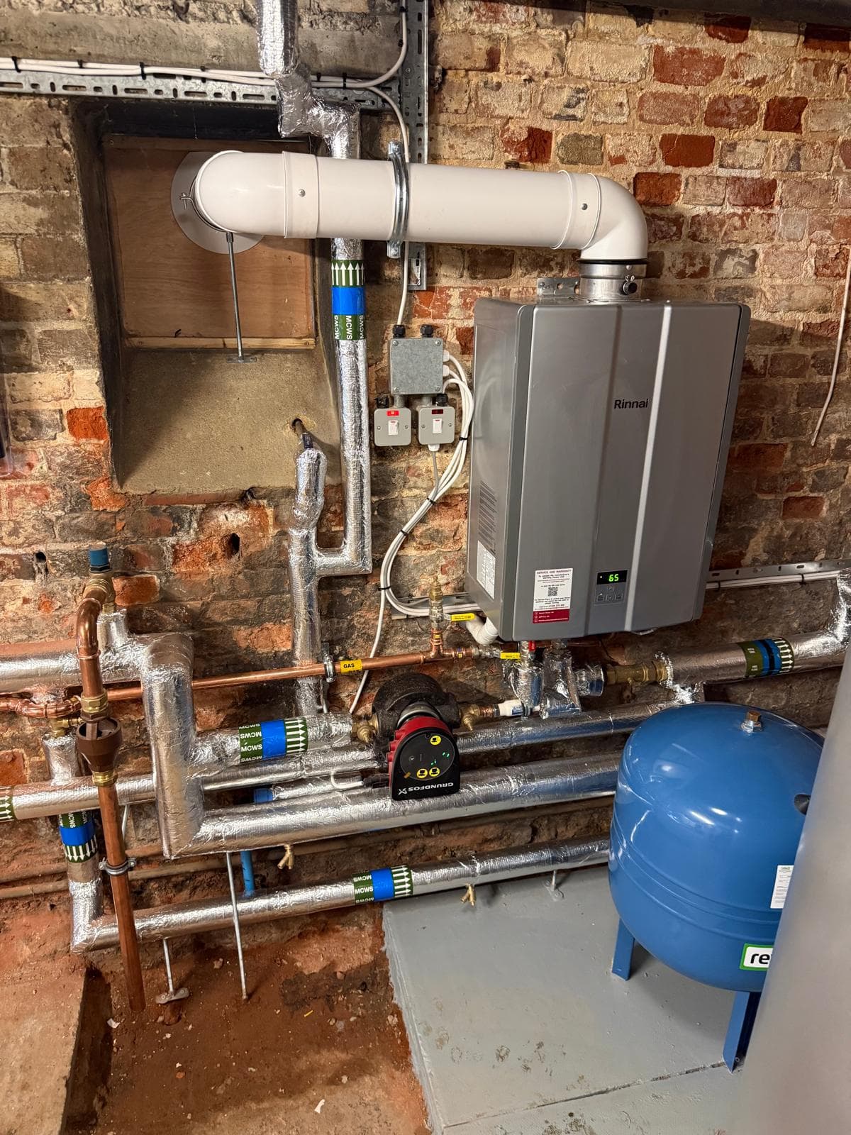 Rinnai continuous-flow water heater with Grundfos pump and labelled cold water and hot water pipework