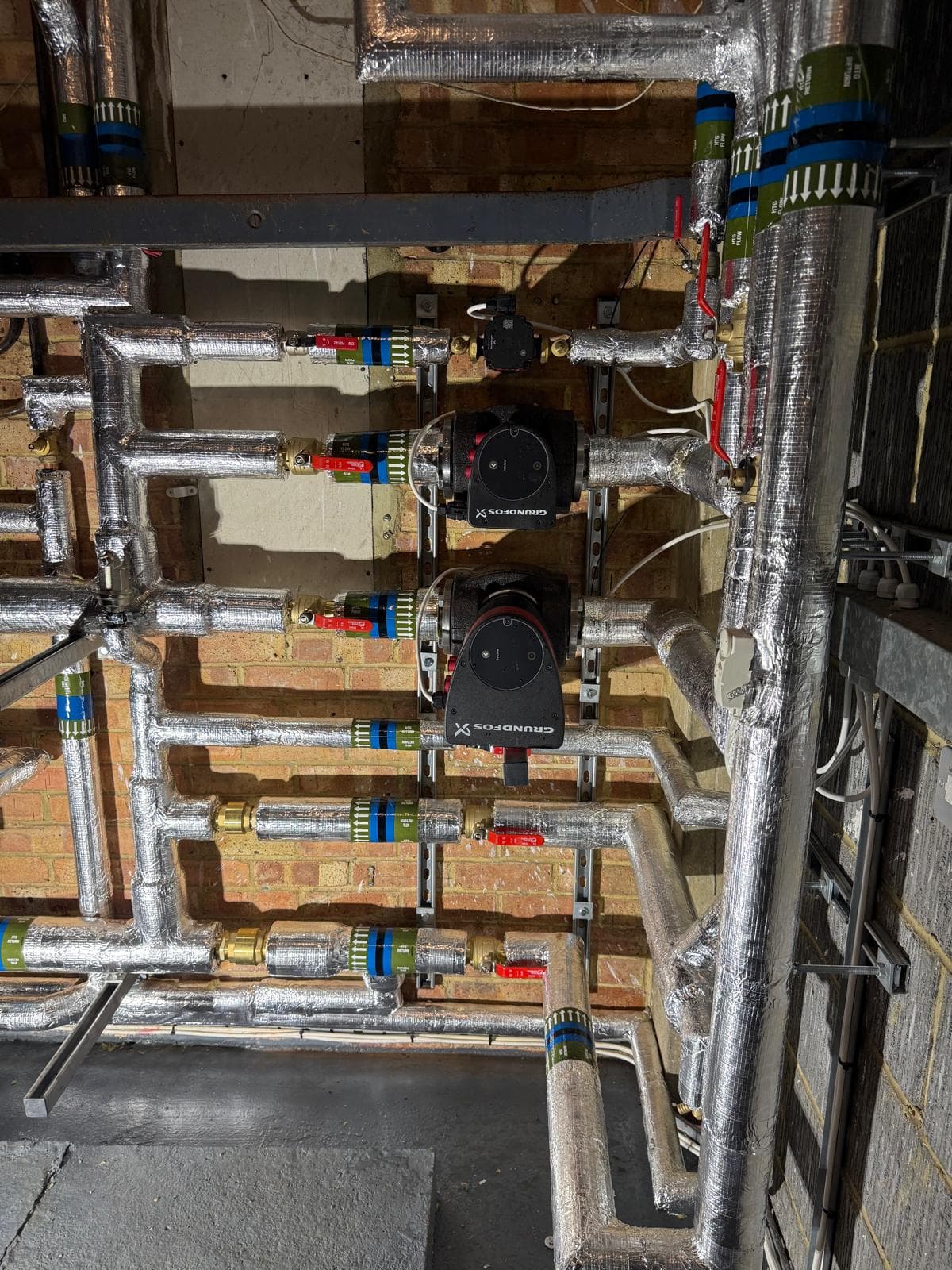 Twin Grundfos pumps on labelled flow and return pipework
